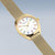 Goldfarbene Armbanduhr mit weißem Zifferblatt, farbigen Stundenmarkern und Milanaiseband