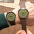 Herrenuhr mit grünem Zifferblatt und braunem Lederarmband, auf dem Handgelenk getragen