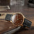 Sternglas Herrenuhr mit schwarzem Lederband, braunes Zifferblatt und goldfarbener Lünette