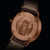 Herrenuhr Rückseite im Detail: bronzefarbenes Gehäuse mit Gravur, braunes Lederband