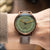 Unisex-Uhr mit grünem Zifferblatt und graubraunem Lederarmband, kupferfarbenes Gehäuse.