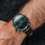 Armbanduhr mit grünem Marmorzifferblatt und braunem Lederarmband am Handgelenk