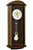 Wanduhr mit dunklem Holzgehäuse und rundem Zifferblatt; sichtbares Pendel