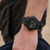 Herrenuhr am Handgelenk: schwarze Sportuhr mit dunklem Zifferblatt und schwarzem Armband.