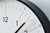 Detail vom weißen Zifferblatt der Wanduhr: schwarze Einfassung, Stundenzeiger.