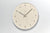 Beige Wanduhr mit silbernem Rahmen, Ziffern und Metallzeigern mit Sekundenzeiger