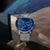 Herrenarmbanduhr mit blauem Zifferblatt und silbernem Mesh-Armband, seitlich am Handgelenk