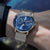 Herrenarmbanduhr mit blauem Zifferblatt und silbernem Mesh-Armband am Handgelenk