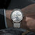 Herrenarmbanduhr mit weißem Zifferblatt, blauen Anzeigen und silbernem Metall-Meshband