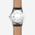 Herrenuhr Rückseite mit kreisförmiger Gravur und schwarzem Lederarmband.
