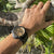 Herren-Armbanduhr am Handgelenk mit beigem Zifferblatt und schwarzem Kautschukband
