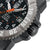 Herrenuhr Detail: geriffelte Lünette und Metallumrandung, orange Zeiger, Datumsfenster bei 31-Tag Anzeige