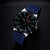 Taucheruhr mit blauem Armband und schwarzem Zifferblatt mit grünen Leuchtmarkierungen