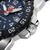 Nahaufnahme Gehäusekante: Edelstahlrücken, geriffelter Chronographenbereich und dunkelblauer Zifferblattlook.