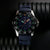 Herrenuhr mit blauem Armband und markantem Leuchtzifferblatt, Edelstahlgehäuse mit Lünette.