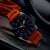 Herrenarmbanduhr mit orangefarbenem Kautschukband, schwarzer Lünette und Leuchtziffern