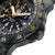 Herrenuhr-Detail mit schwarzem Armband und geriffelter Lünette am Gehäuse.
