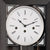 Großaufnahme Zifferblatt einer Wanduhr mit weißer Skala, schwarzen Zeigern und römischen Ziffern