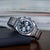 Herrenuhr mit silbernem Metallarmband, rundem Gehäuse und Chronograph-Zifferblatt