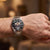 Festina Herrenarmbanduhr mit schwarzem Zifferblatt und silbernem Metallarmband am Handgelenk