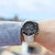 Sportliche Herrenuhr am Handgelenk mit schwarzem Zifferblatt und Metallband