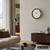 Wanduhr an Wand mit braun-goldenem Ornamentrand, goldenen Ziffern und schwarzen Zeigern