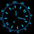 Nahaufnahme Zifferblatt: blau leuchtende Indizes einer Herrenuhr.