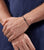 Graues Armband am Handgelenk mit feiner Gliederkette und kleinem Logo-Anhänger