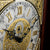 Uhrzifferblatt der Standuhr mit römischen Ziffern, goldverziert und geschwärzten Zeigern