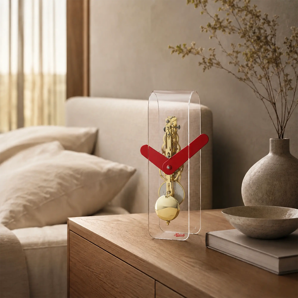 Tischuhr im transparenten Acrylgehäuse mit rotem Zeigersystem und goldener Pendelkugel