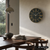 Wanduhr an der Wand: rundes Design, dunkles Zifferblatt, goldfarbene Linien und AMS-Logo