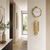Goldfarbene Wanduhr mit Zierpendeln an der Wand im Flur