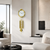 Goldfarbene Wanduhr mit Zierpendeln an weißer Wand