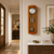 Wanduhr an der Wand aus Holz mit rundem Zifferblatt, Glas und Metallpendeln