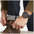 Herrenuhr am Handgelenk mit schwarzem Armband und dunklem Zifferblatt.