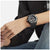 Herrenuhr am Handgelenk mit schwarzem Armband und leuchtenden Ziffern auf dem Zifferblatt.