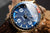 Herrenuhr im Detail: blaues Zifferblatt mit Leuchtzeigern, goldfarbenes Gehäuse
