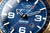 Herrenuhr-Zifferblatt im Nahblick mit blauer Oberfläche, großen Ziffern und Zeigern