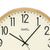 Wanduhr-Ziffernblatt im Detail: beiges Blatt, schwarze 12 und Zeiger, heller Holzrand.