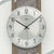 Nahaufnahme Wanduhr: weißes Zifferblatt mit AMS-Schriftzug und schwarzen Zeigern