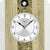 Detail der Wanduhr: weißes Zifferblatt mit Ams.-Logo und schwarzen Zeigern im Holzhaus-Rahmen