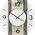 Wanduhr-Detail: Zeiger und römische Ziffern auf Naturstein-Holzdekor, facettiertes Glas