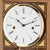 Wanduhr-Zifferblatt mit Hermle-Logo, goldfarbener Rahmen, römische Zahlen, Nahaufnahme.